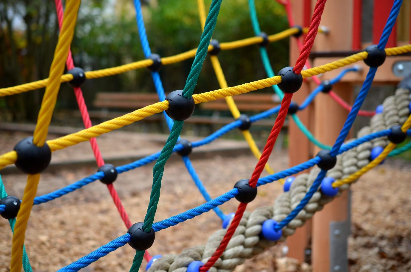 Rete di arrampicata multicolore di un'area gioco, con fondo in corteccia
