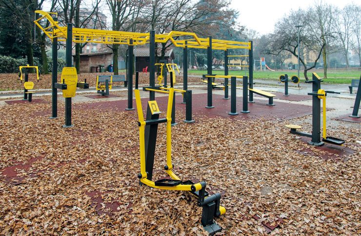 Area fitness all'aperto con attrezzature gialle e nere su fondo in gomma
