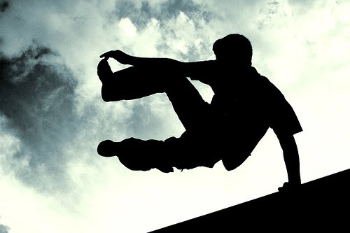 Sagoma di un atleta di parkour in volo sopra una struttura, controluce