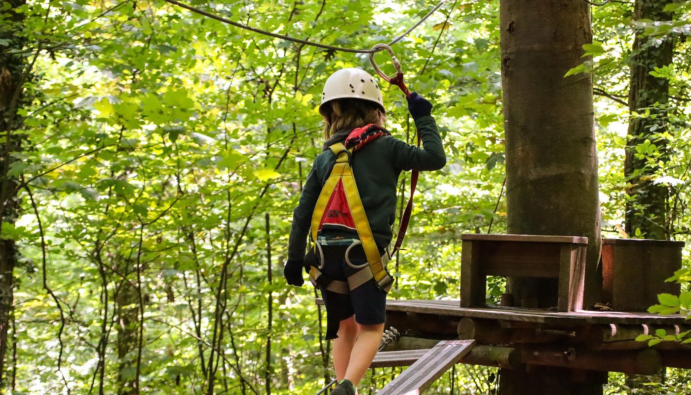 Passaggio su un percorso acrobatico in un bosco, con la linea di sicurezza in acciaio sopra la piattaforma