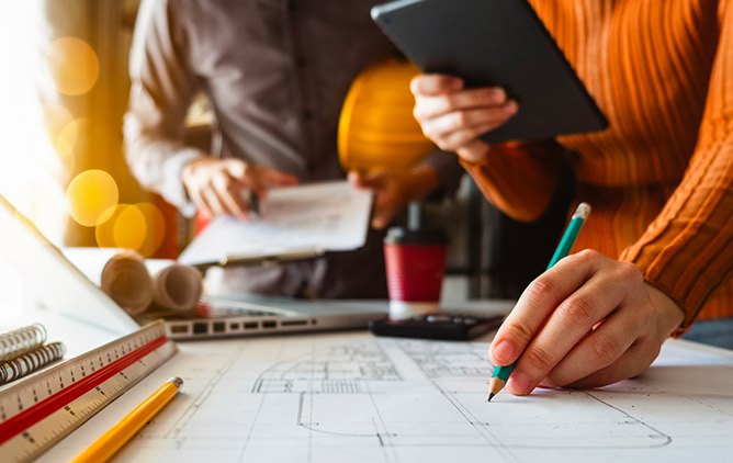 Due professionisti al lavoro su elaborati grafici e capitolati