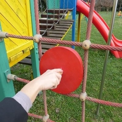Sagoma di prova tenuta in mano davanti alla rete di una struttura da gioco, durante un'ispezione